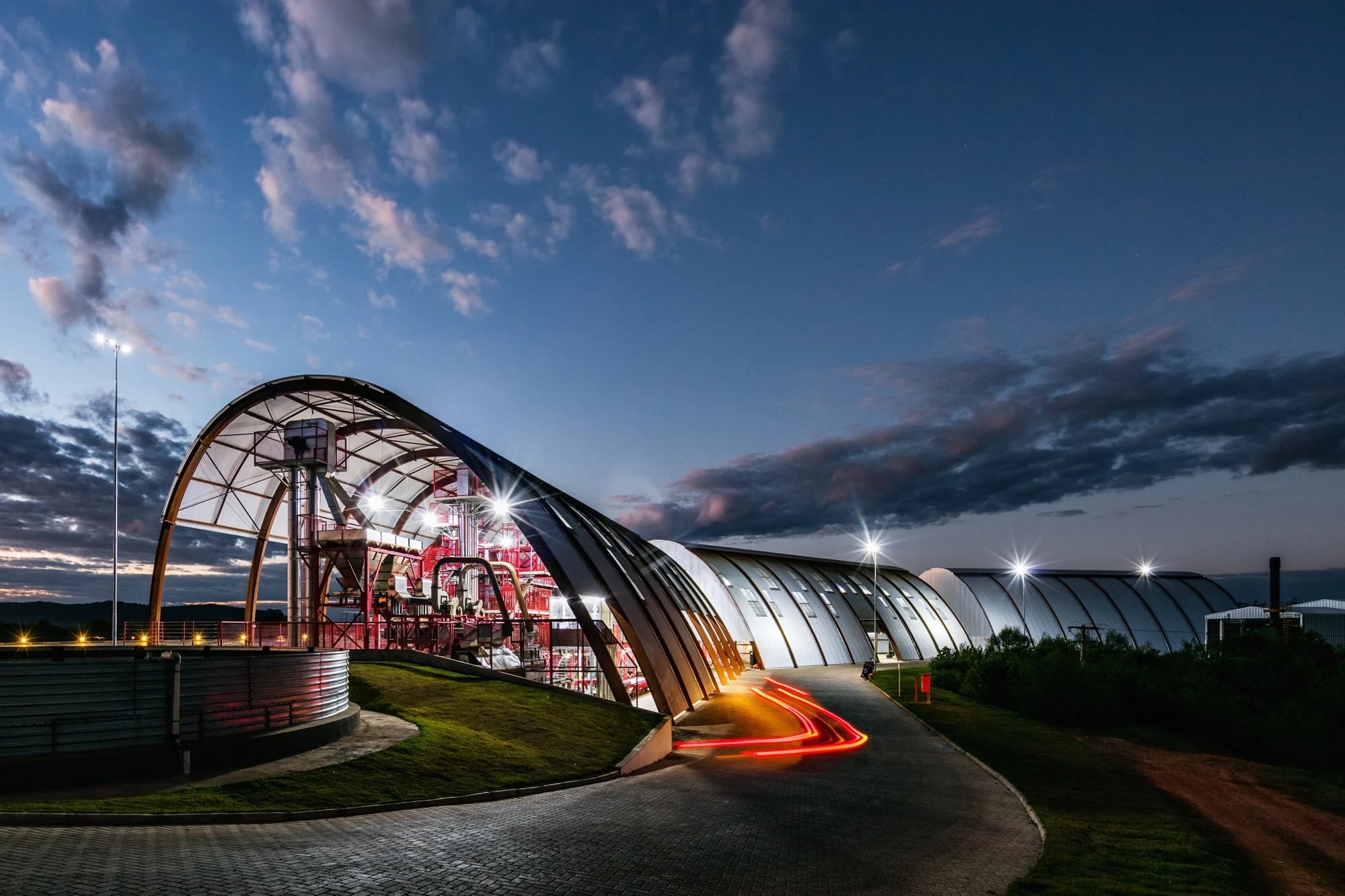 Arquitetura de cobertura curva da Fazenda Rio Verde, iluminada ao anoitecer